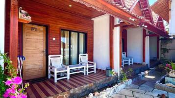 A wooden building with a porch, a door, and a seating area with chairs.