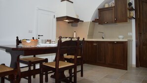 Une cuisine avec des meubles de rangement en bois, une table à manger avec des chaises et une porte blanche.