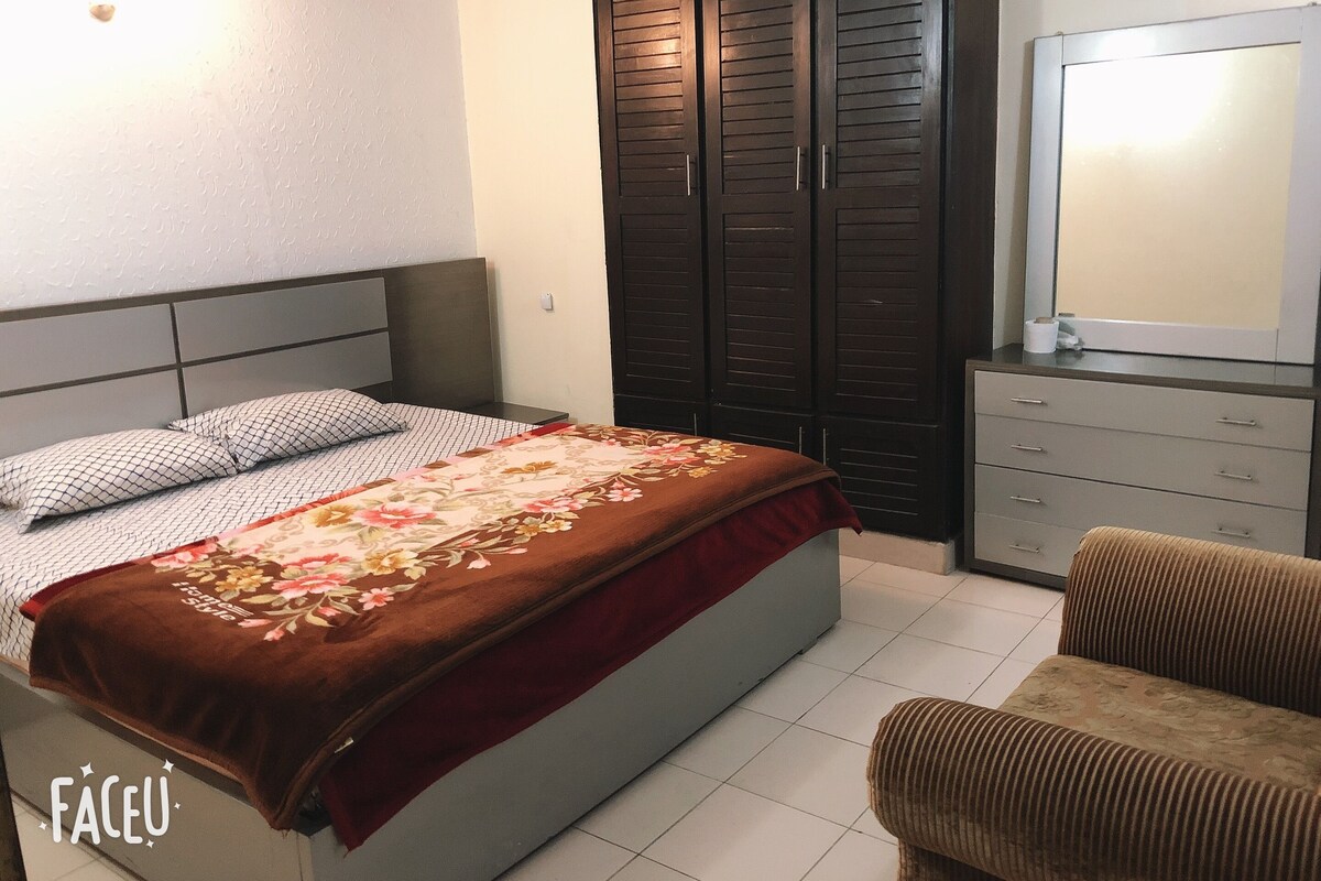 A bedroom with a bed, a wardrobe, a television, and a sofa.