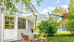 Un patio con tavolo e sedie, un ombrellone e un piccolo giardino.