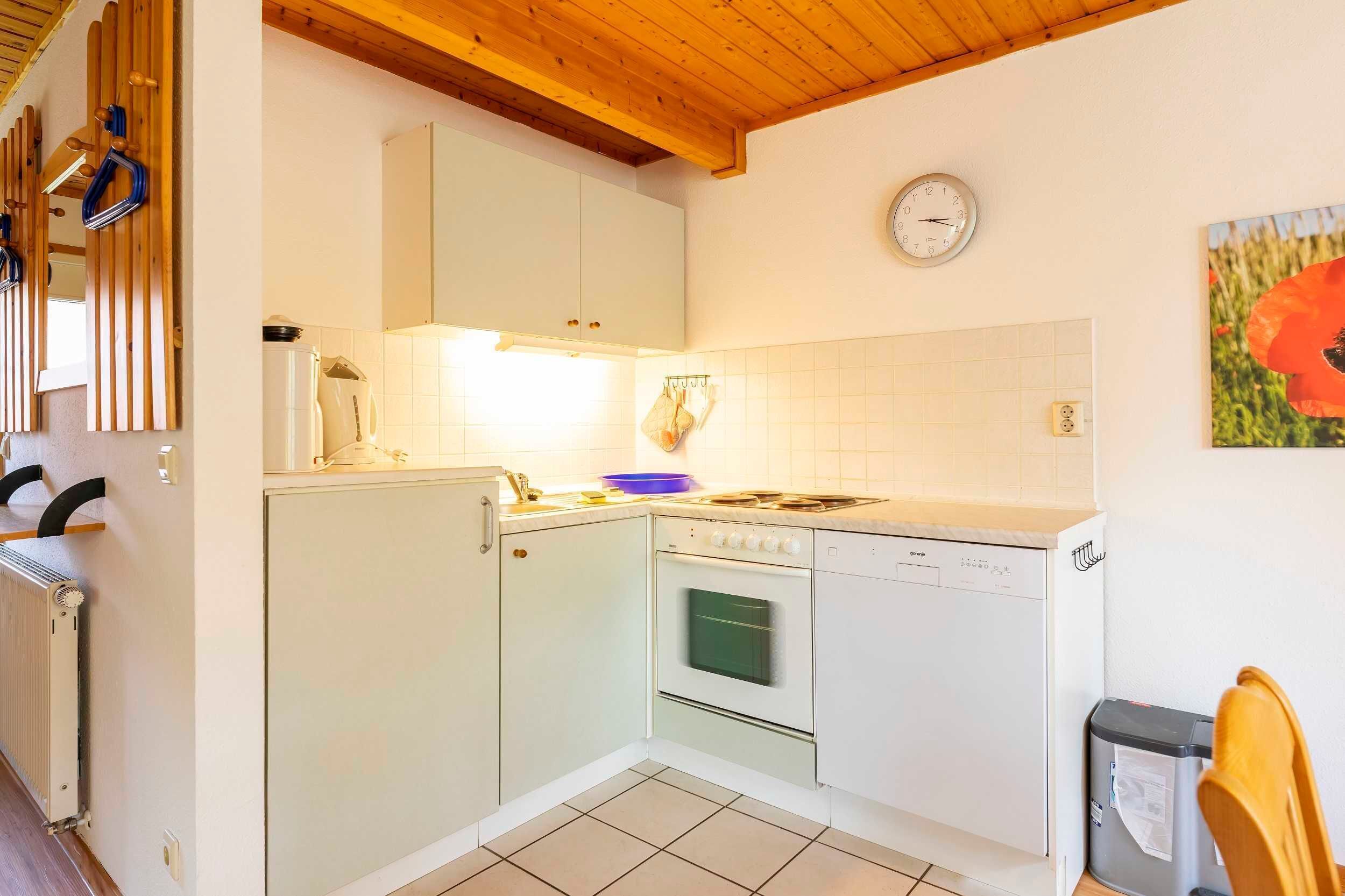 A compact kitchen with white cabinets, a stove, an oven, and a dishwasher.
