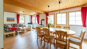 A cozy room with a wooden ceiling, a dining table with chairs, a sofa, and a radiator.