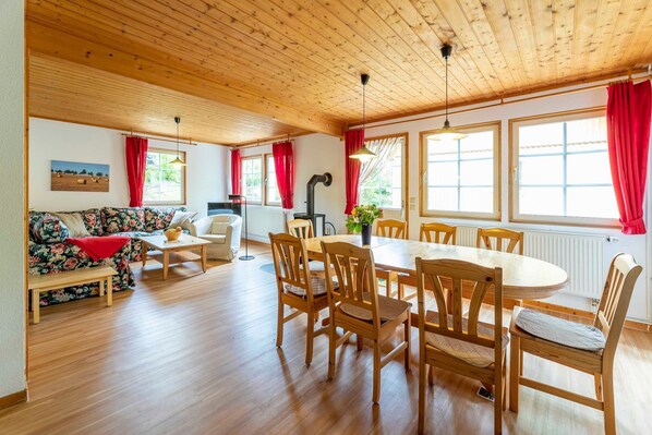 Une pièce chaleureuse avec un plafond en bois, une table à manger avec des chaises, un canapé et un radiateur.