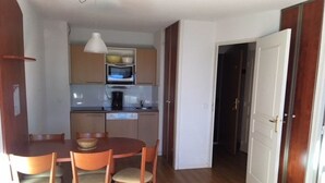 Una cocina compacta con comedor, piso de madera y una puerta blanca.