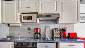 Eine Küche mit weißen Schränken, einer Mikrowelle, einer Kaffeemaschine, einem Toaster und einem Kühlschrank.