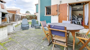 Eine Terrasse mit einem runden Holztisch, vier Stühlen, einer kleinen Holzbank und einem Holzzaun.