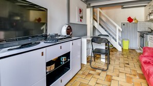 Eine kompakte Küche mit modernen Geräten, ein Essbereich mit einem Stuhl und eine Treppe, die in eine weitere Ebene führt.