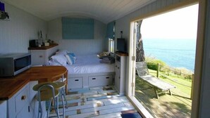 Une chambre à coucher avec un lit, un bureau, une chaise et une vue sur la mer.
