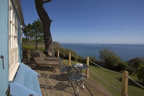Enjoy a serene ocean view from this comfortable outdoor seating area with a bench and table.