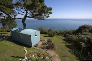 Situated on a grassy slope, this cabin offers a serene view of the surrounding water.