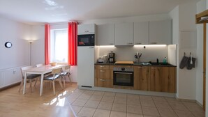 Una cocina compacta con comedor, que incluye una mesa con sillas, microondas, cafetera y hervidor.