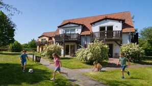 A residential building with a red-tiled roof, a balcony, and a paved pathway.