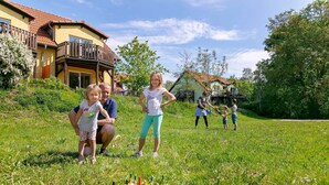 Una familia jugando en un jardín con una casa al fondo.