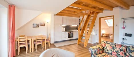 Un espace de vie de style loft comprenant une cuisine, un coin repas et un escalier.