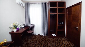 A hotel room with a desk, chair, air conditioning unit, wardrobe, and a patterned carpet. - Hotel Golden Square Bishkek (Bishkek)