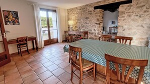 A dining area with a large table, chairs, and a stone wall.