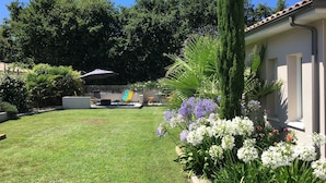 A well-maintained garden with a lawn, various plants, and a patio area with outdoor furniture.
