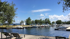 A marina with boats docked, a wooden deck, and a grassy area.