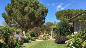 A well-maintained garden with a variety of plants and flowers, a lawn, and a house with a tiled roof.