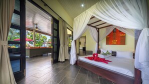 Una stanza con un letto, una tenda a baldacchino, vista attraverso una porta vetrata e un asciugamano rosso sul letto.