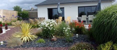 A modern house with a well-maintained garden featuring various plants and flowers.