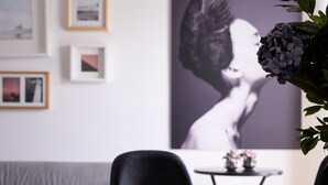 A modern living room with a sofa, a coffee table with books, and a large framed artwork on the wall. - Parthenon 2BD Apartment (Athens)