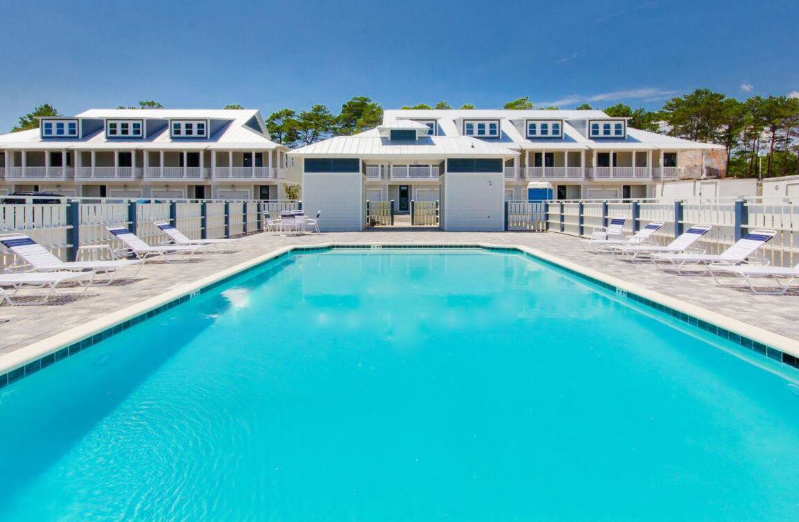 Une piscine avec des chaises longues et un bâtiment doté de nombreux balcons.
