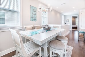 Uma sala de jantar com uma mesa branca, seis cadeiras e um candelabro.