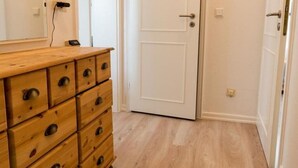 A room with a wooden dresser, a white door, and a light-colored wooden floor. - Südstrand 3, Germany (Sylt)