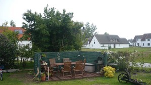 Un jardin avec une terrasse en bois, du mobilier d’extérieur et un barbecue.