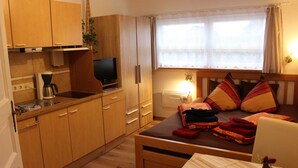 Une chambre de taille réduite comprenant un lit, une table de chevet et une petite kitchenette.