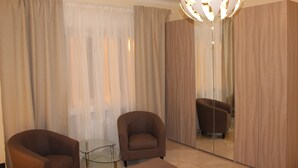 Una habitación moderna con dos sillones, una mesa de vidrio y un espejo grande que refleja el espacio.