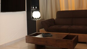 Una sala de estar moderna con un sofá marrón, una mesa de centro de madera y una lámpara de araña original.