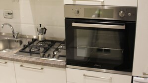 Una cocina con campana extractora de acero inoxidable, horno empotrado y un lavamanos.