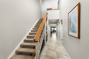Eine Treppe mit hölzernem Geländer und Teppichstufen, die zu einer Zwischenebene führt.