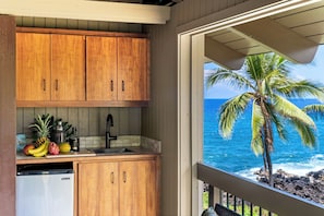 A kitchen with wooden cabinets and a view of the ocean.