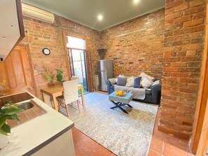 A kitchen with a sink, a dining table with chairs, a sofa, and a decorative bowl on a coffee table. - ***Fitzroy cottage- 3/4brms- 2baths. 2km city**** (fitzroy)
