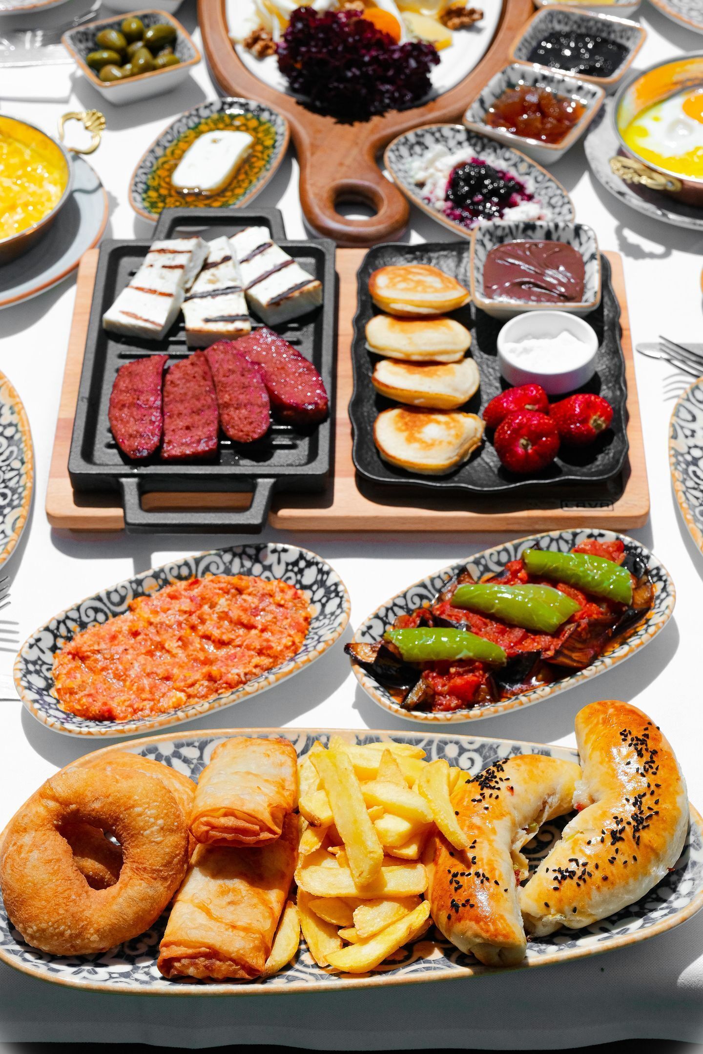 A variety of dishes including sausages, pastries, and vegetables on a table.