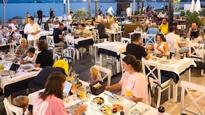 An outdoor dining area with tables and chairs, overlooking a body of water.