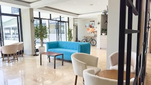 A modern lobby with a blue sofa, white armchairs, and a wooden coffee table.