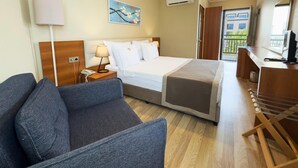 A hotel room with a bed, a desk, a chair, a lamp, and a ceiling fan.