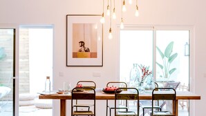 Uma sala de estar moderna com um sofá, cadeiras, uma mesa de jantar e um lustre.