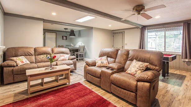 A living room with two brown leather sofas, a wooden coffee table, and a red rug. - The Flo's house, Snowbird Winter Haven • Spacious 1800 sq ft Home with New Lanai (Tampa)