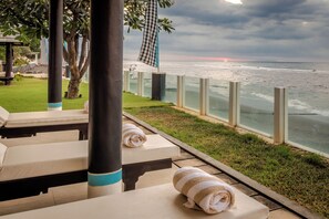 A beachside lounge area with sun loungers and towels, overlooking the ocean.