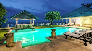 A pool area with lounge chairs, a gazebo, and a view of the ocean at night. - Beachfront pool villa: Free welcome dinner! With own boat! (Dencarik)