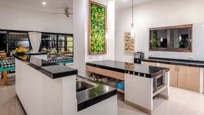 A modern kitchen with a central island, a dining area with a checkered tablecloth, and a large window with curtains.