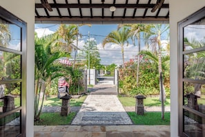 A pathway leading to a gated entrance with a pergola overhead, surrounded by lush greenery and palm trees. - Beachfront pool villa: Free welcome dinner! With own boat! (Dencarik)