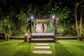 A garden with a stone bench, a pathway, and a pergola with lights. - Luxury 6BR Beachfront Villa with Private Pool! (Dencarik)