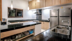 A modern kitchen with stainless steel appliances, wooden cabinets, and pendant lighting.
