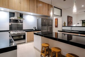 A modern kitchen with stainless steel appliances, wooden cabinets, and a black countertop.